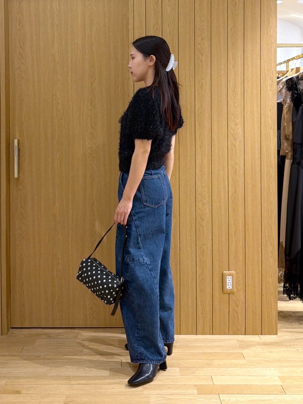 ブルー系のデニムパンツ、ブラック系のニット/セーター、ブラック系のハンドバッグを着用したレディースの秋コーディネートの2枚目の写真