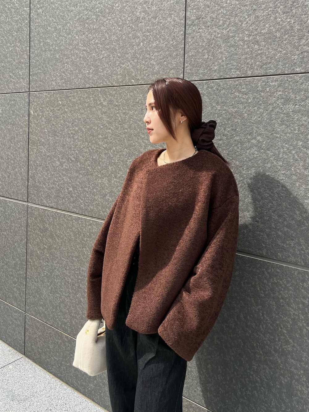 ブラック系のデニムパンツ、ホワイト系のハンドバッグ、ブラウン系のTシャツ/カットソーを着用したレディースの秋コーディネートの4枚目の写真