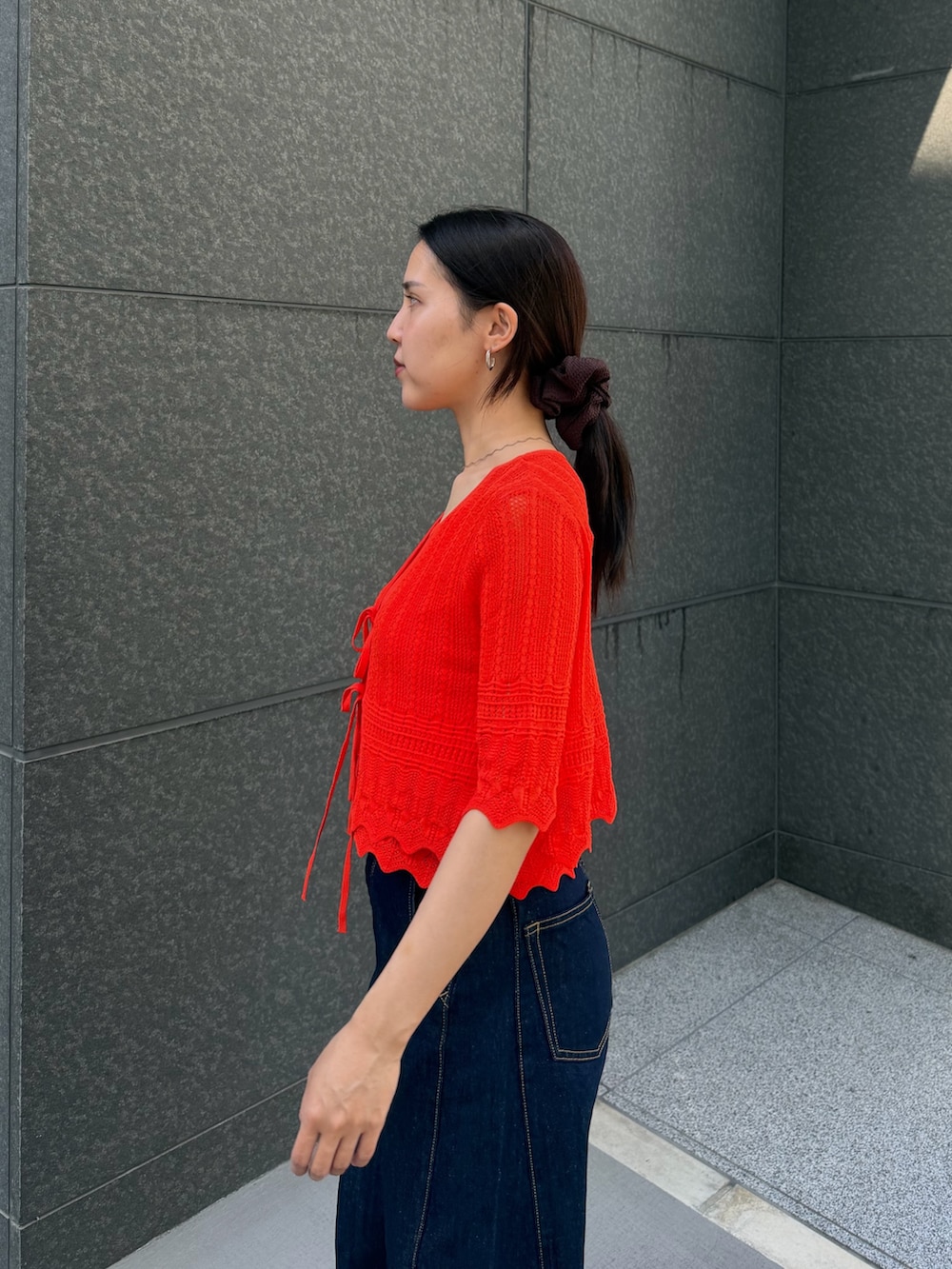 ブルー系のデニムパンツ、オレンジ系のアンサンブルを着用したレディースの春コーディネートの5枚目の写真