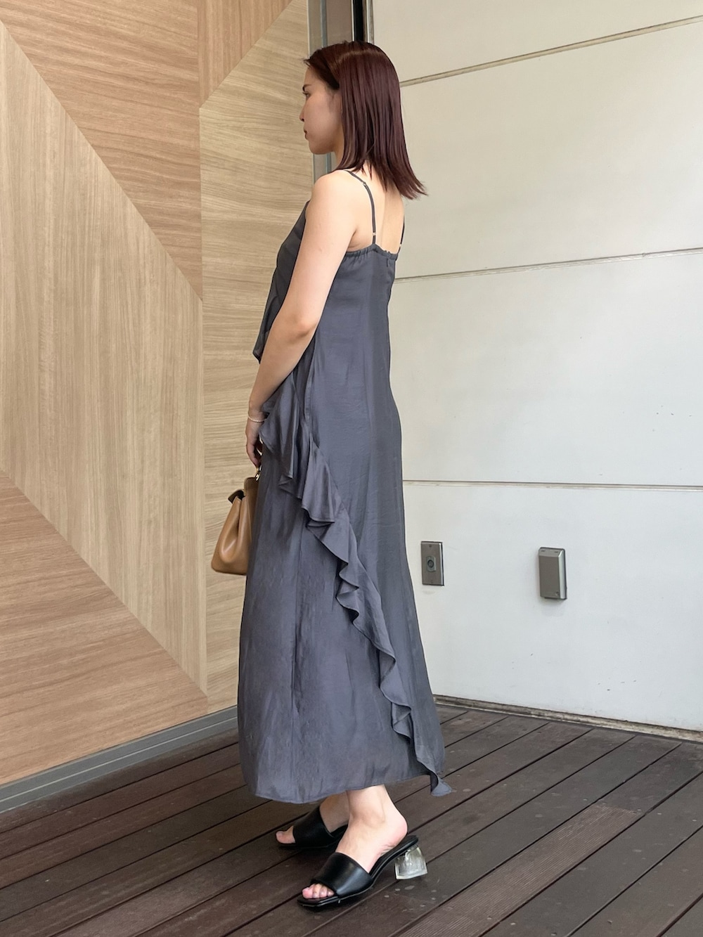 グレー系のワンピース、ブラウン系のハンドバッグ、ブラック系のサンダルを着用したレディースの夏コーディネートの2枚目の写真