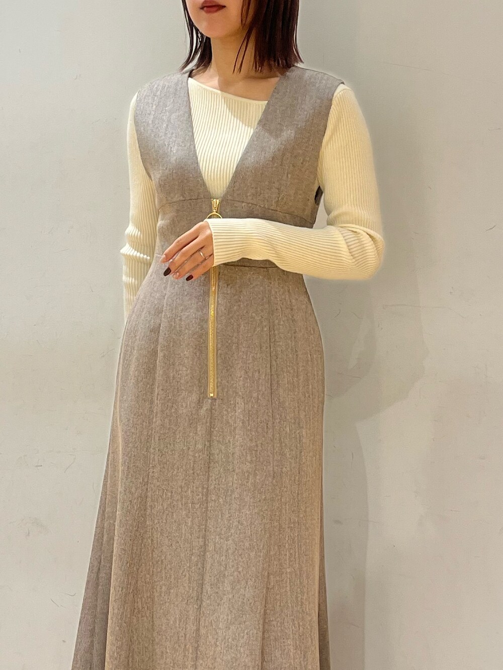 ブラック系のブーツ、ホワイト系のニット/セーター、ベージュ系のジャンパースカートを着用したレディースの冬コーディネートの4枚目の写真