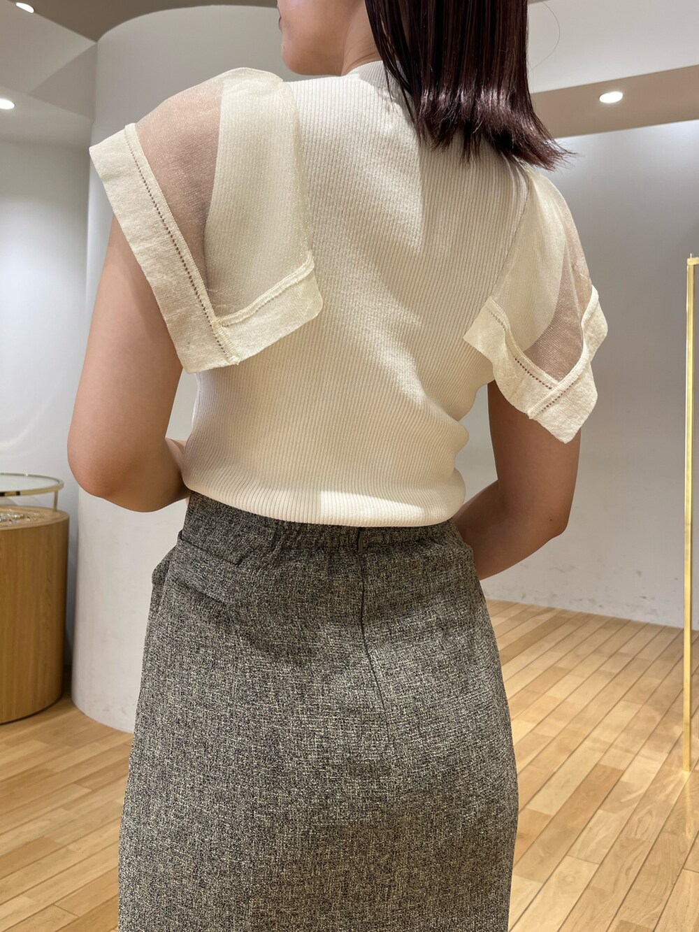 ブラウン系のハンドバッグ、ブラウン系のスカート、ホワイト系のニット/セーターを着用したレディースの春コーディネートの6枚目の写真