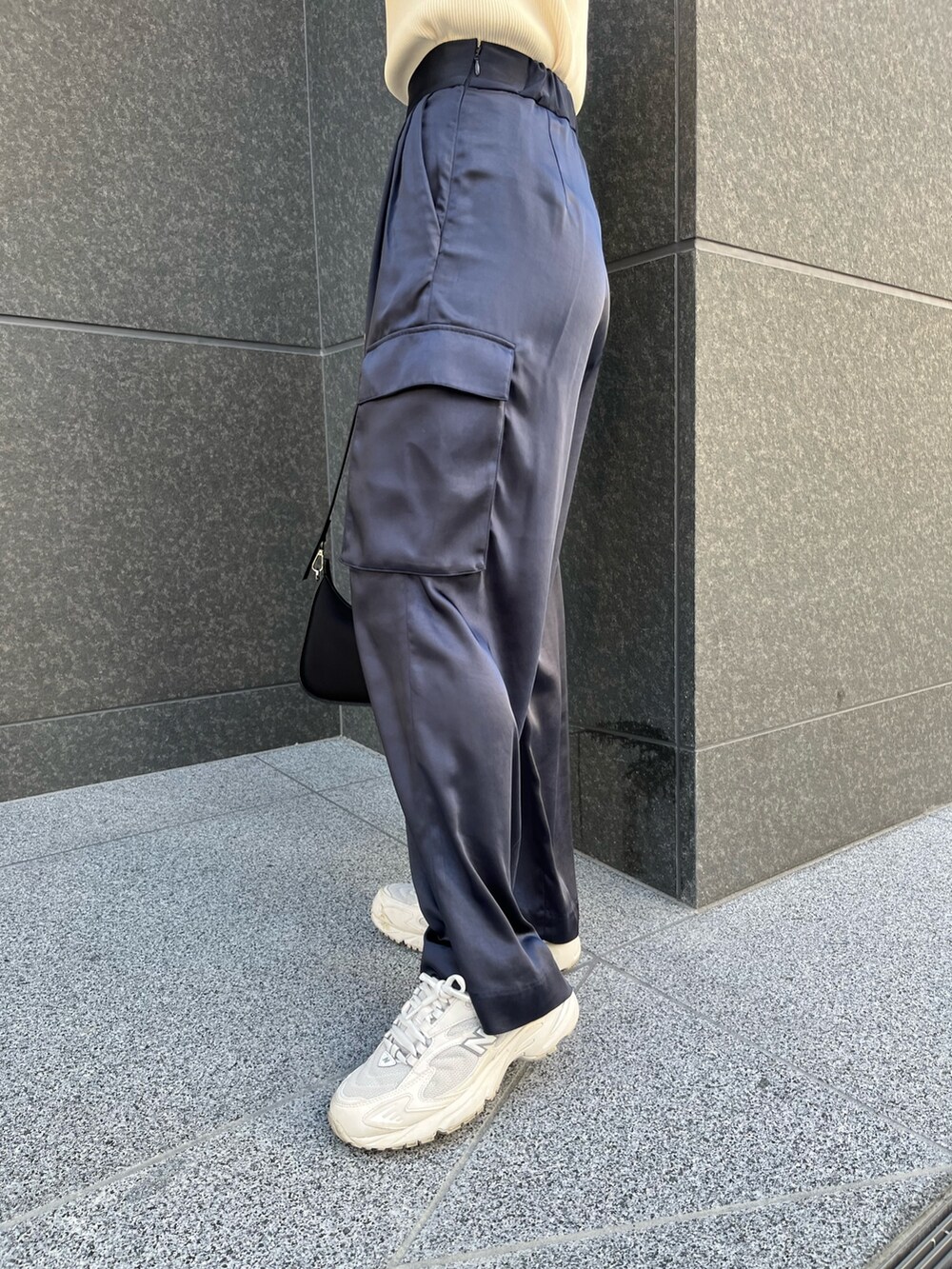 ブラック系のハンドバッグ、ブルー系のカーゴパンツ、ホワイト系のニット/セーターを着用したレディースの春コーディネートの7枚目の写真