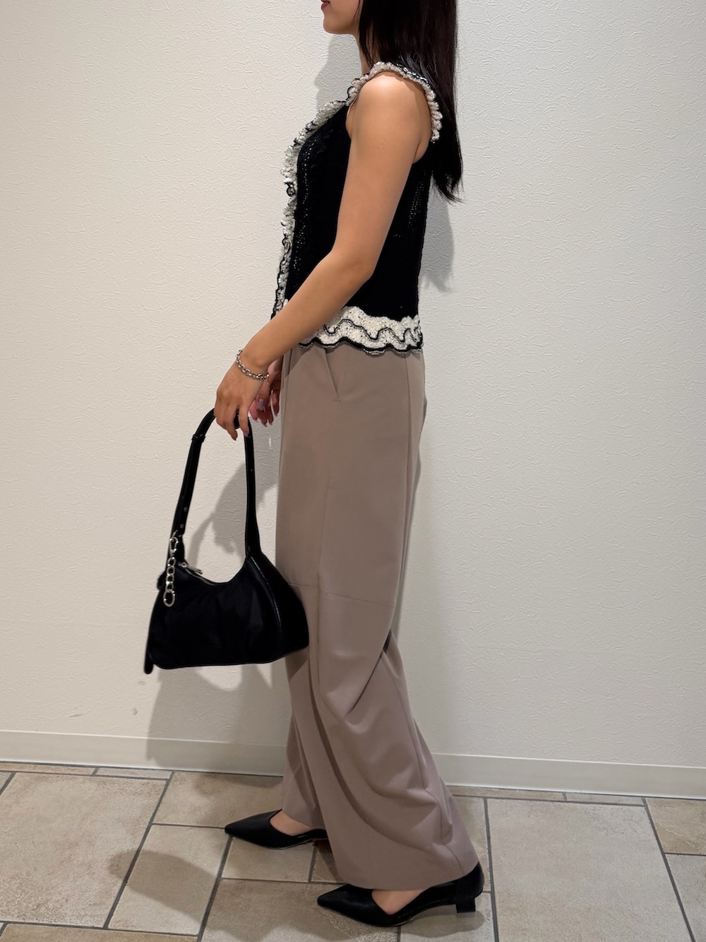 ベージュ系のその他パンツ、ブラック系のニット/セーター、ブラック系のハンドバッグを着用したレディースの夏コーディネートの2枚目の写真