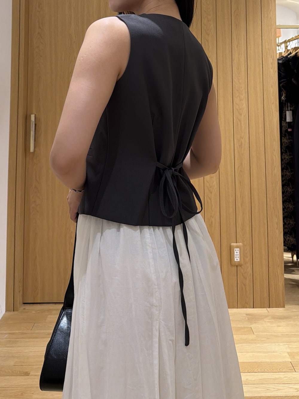ブラック系のパンプス、グレー系のワンピース、ブラック系のハンドバッグを着用したレディースの夏コーディネートの5枚目の写真