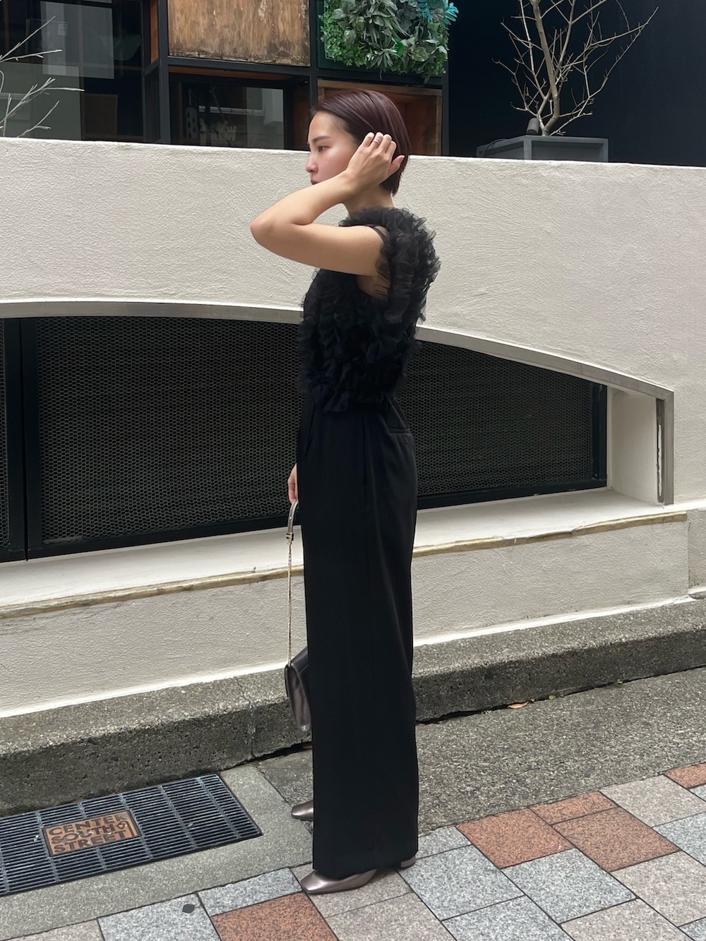 ブラック系のパンツドレス、その他のパンプス、シルバー系のハンドバッグを着用したレディースの冬コーディネートの2枚目の写真