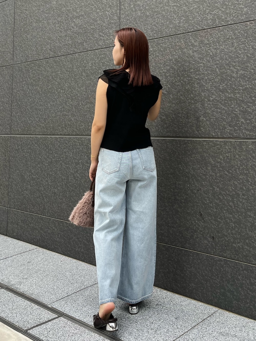 ブラック系のニット/セーター、ブルー系のデニムパンツ、ベージュ系のボストンバッグを着用したレディースの夏コーディネートの3枚目の写真