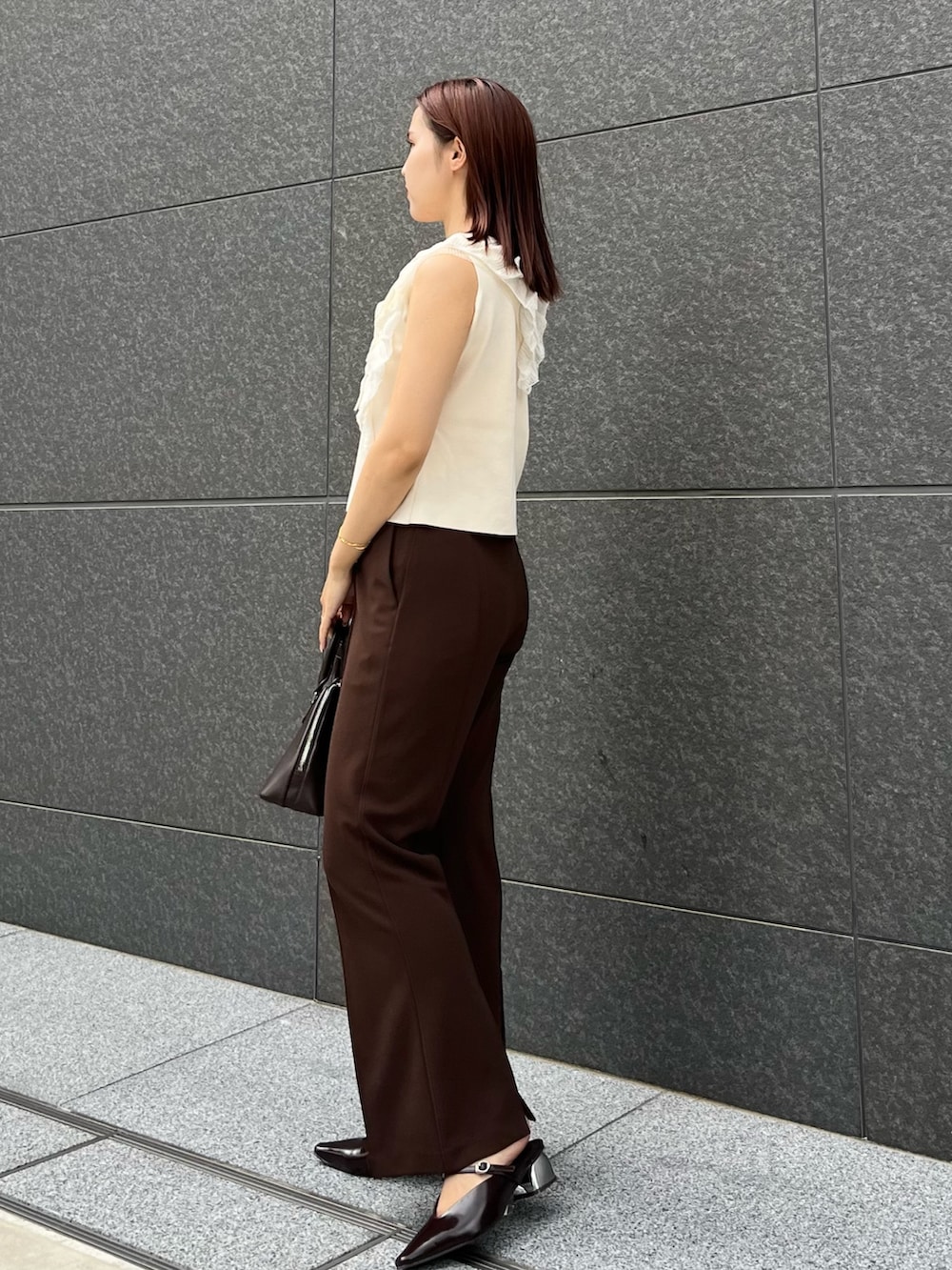 ホワイト系のニット/セーター、ブラウン系のその他パンツ、ブラウン系のボストンバッグを着用したレディースの夏コーディネートの2枚目の写真