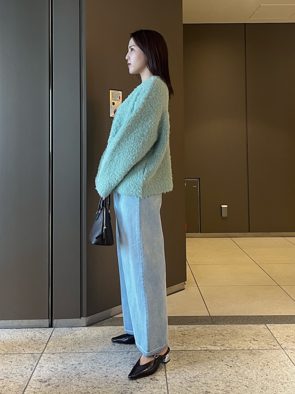 ブルー系のデニムパンツ、ブラウン系のパンプス、ブラウン系のボストンバッグを着用したレディースの夏コーディネートの2枚目の写真