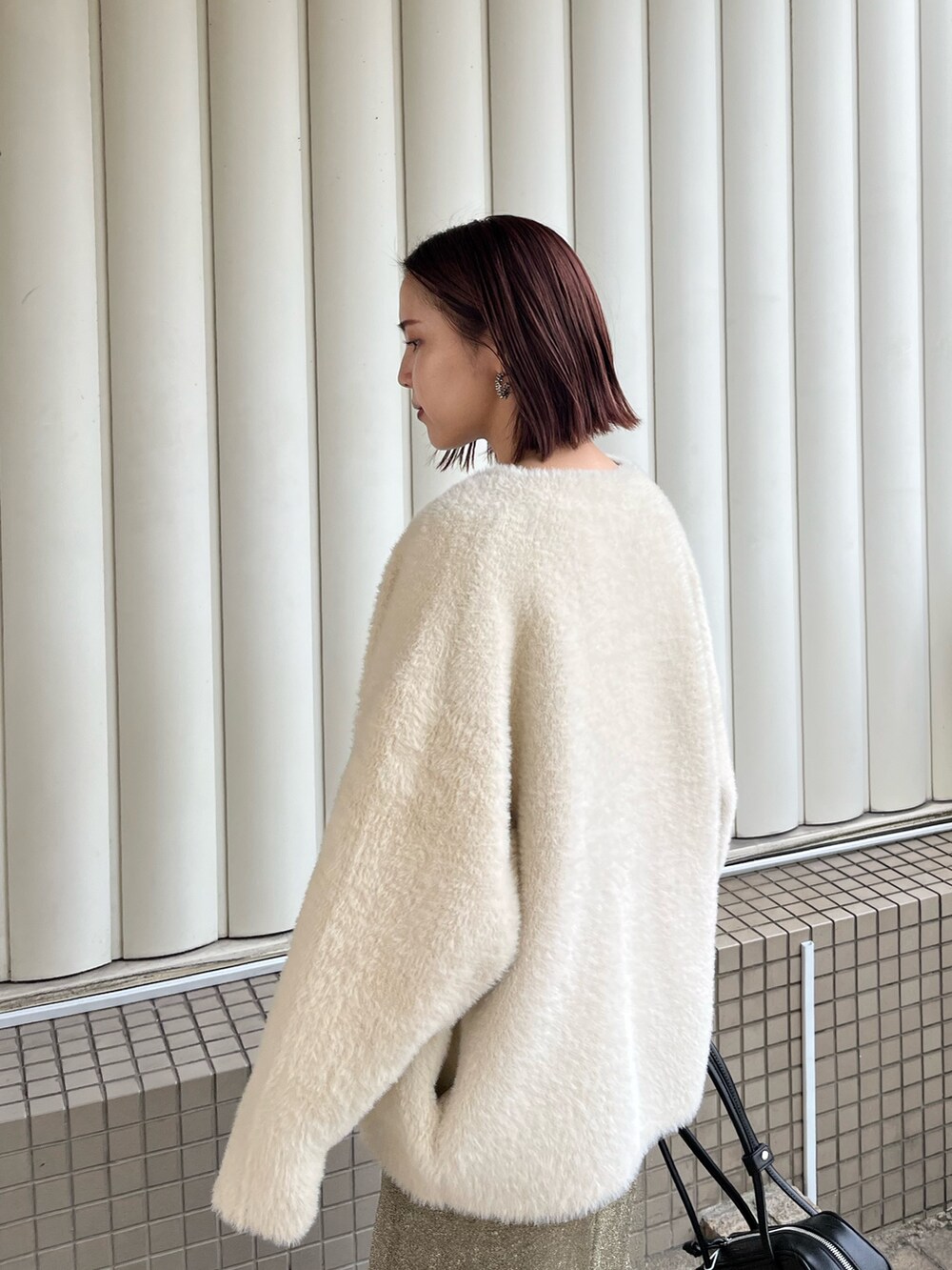 ホワイト系のカーディガン/ボレロ、ゴールド系のスカート、ブラック系のニット/セーターを着用したレディースの冬コーディネートの6枚目の写真