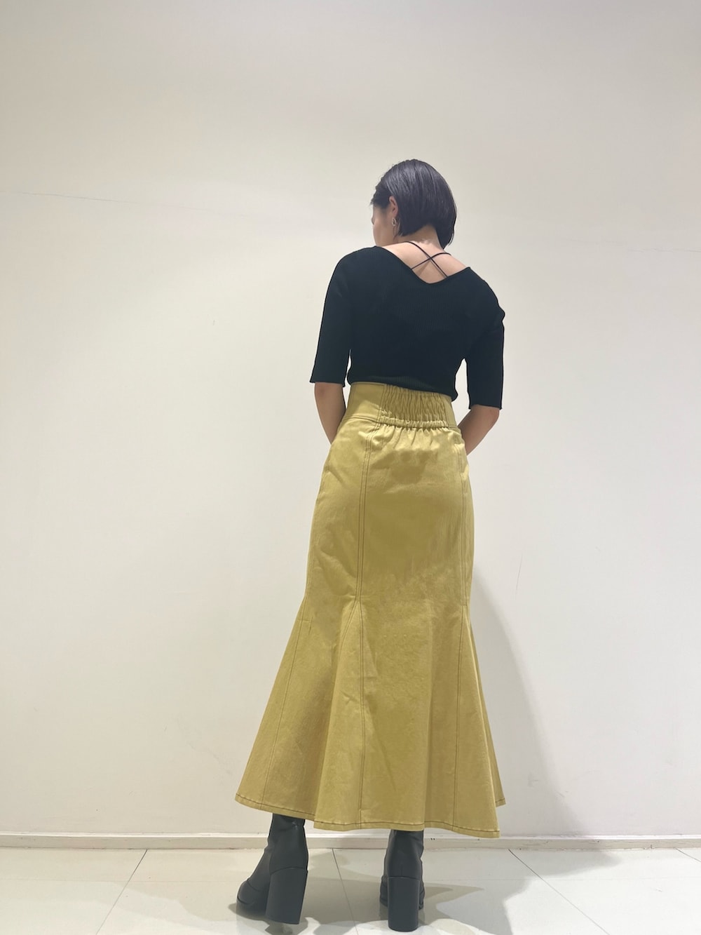 イエロー系のスカート、ブラック系のハンドバッグ、ブラック系のニット/セーターを着用したレディースの秋コーディネートの3枚目の写真