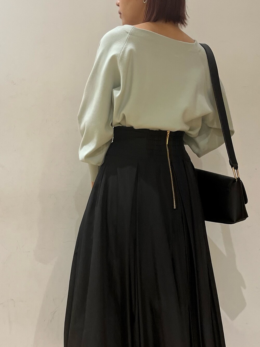 ブラック系のブーツ、ブラック系のスカート、グリーン系のニット/セーターを着用したレディースの冬コーディネートの5枚目の写真