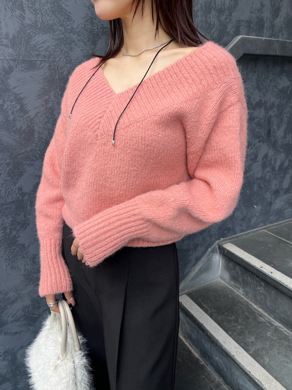 ブラック系のブーツ、ピンク系のニット/セーター、ホワイト系のボストンバッグを着用したレディースの秋コーディネートの5枚目の写真