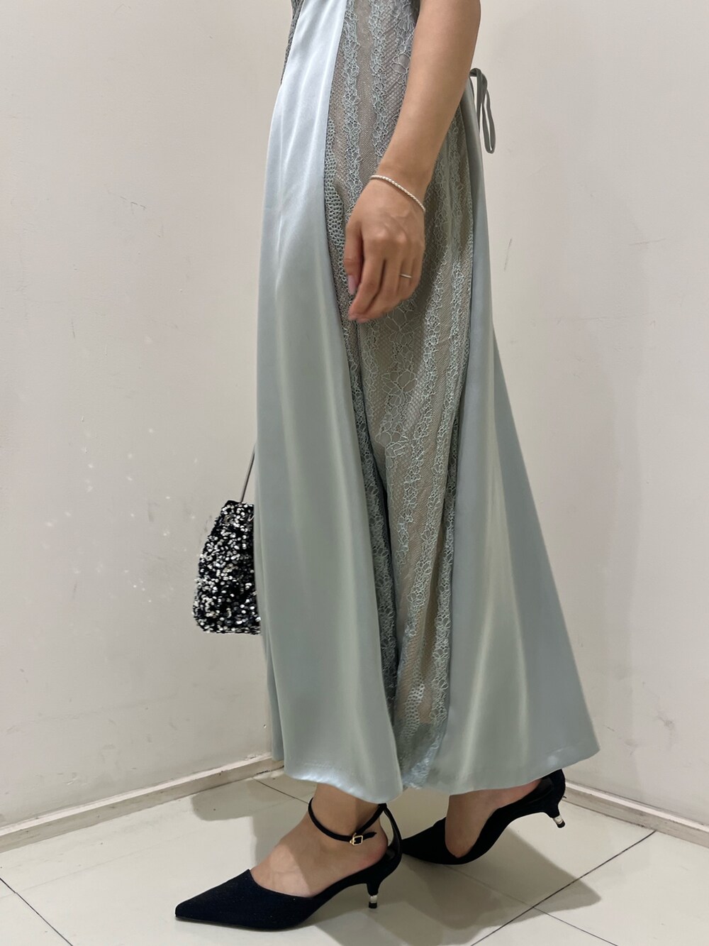 シルバー系のハンドバッグ、ブラック系のパンプス、グリーン系のドレスを着用したレディースの秋コーディネートの7枚目の写真