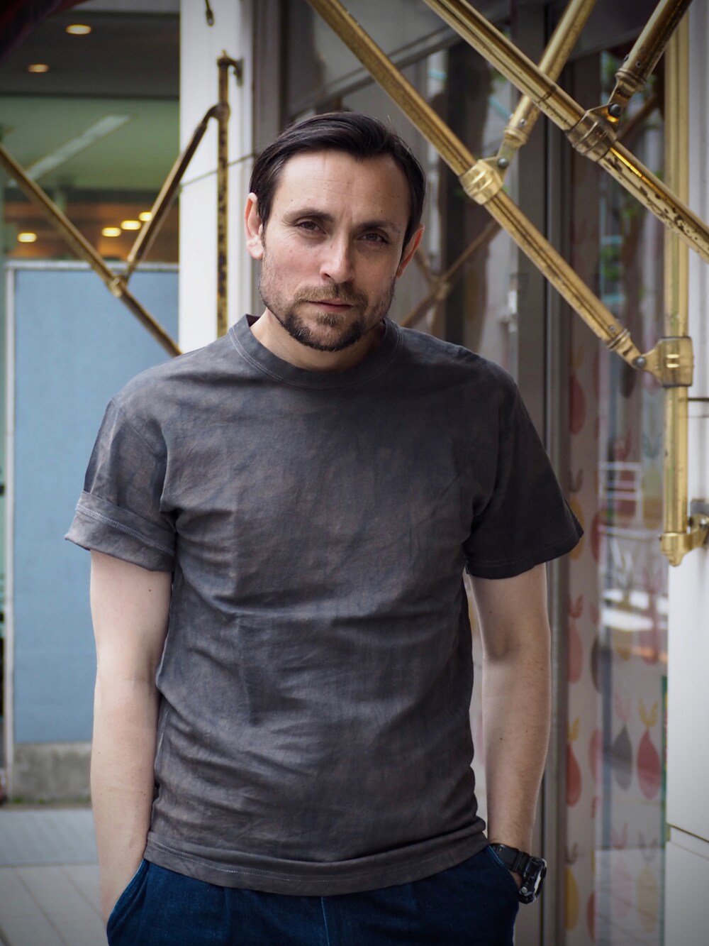 グレー系のTシャツ/カットソー、ブルー系のデニムパンツ、ブラック系のデジタル腕時計を着用したメンズの春コーディネートの2枚目の写真