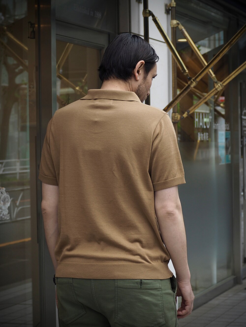 ブラウン系のポロシャツ、ブラック系のデジタル腕時計を着用したメンズの春コーディネートの4枚目の写真