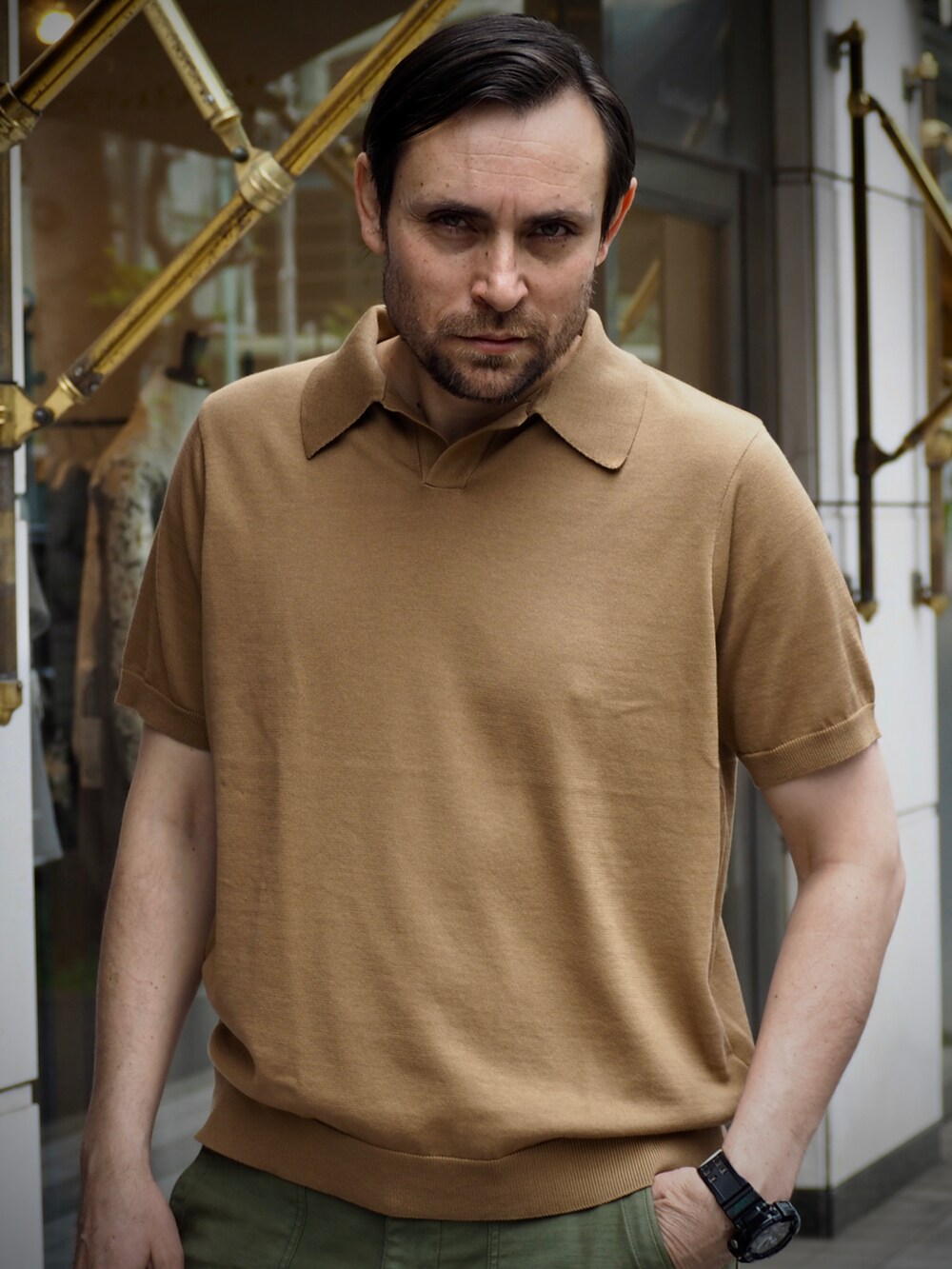 ブラウン系のポロシャツ、ブラック系のデジタル腕時計を着用したメンズの春コーディネートの2枚目の写真