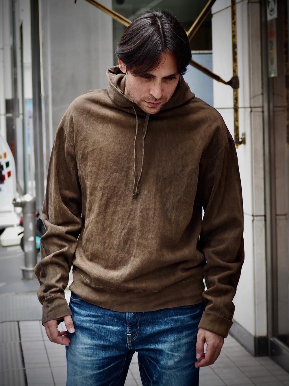 ブラウン系のパーカー、ブルー系のデニムパンツを着用したメンズの春コーディネートの2枚目の写真