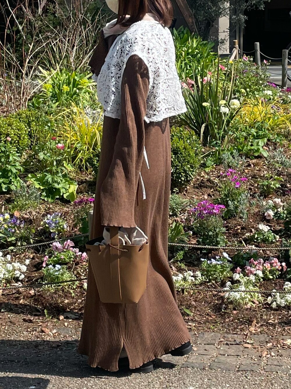 ホワイト系のベスト、ブラウン系のショルダーバッグ、ブラック系のローファーを着用したレディースの春コーディネートの2枚目の写真