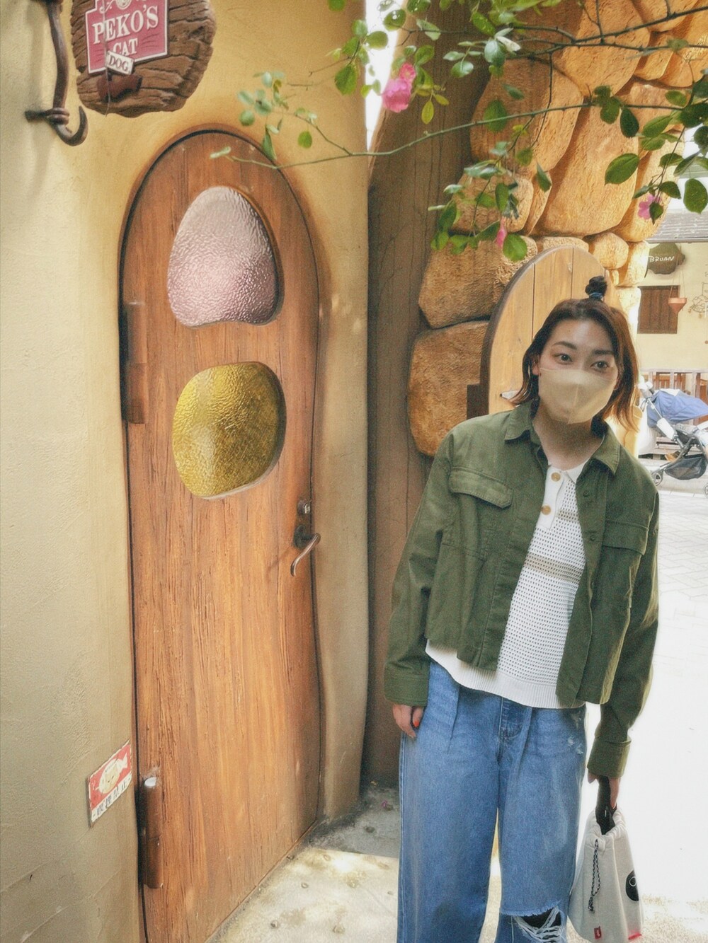 グリーン系のミリタリージャケット、ホワイト系のトップス、ブルー系のデニムパンツを着用したレディースの春コーディネートの4枚目の写真