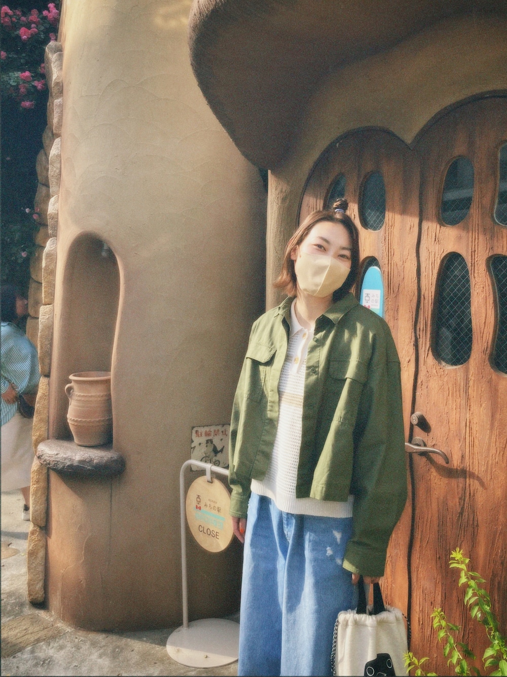 グリーン系のミリタリージャケット、ホワイト系のトップス、ブルー系のデニムパンツを着用したレディースの春コーディネートの3枚目の写真