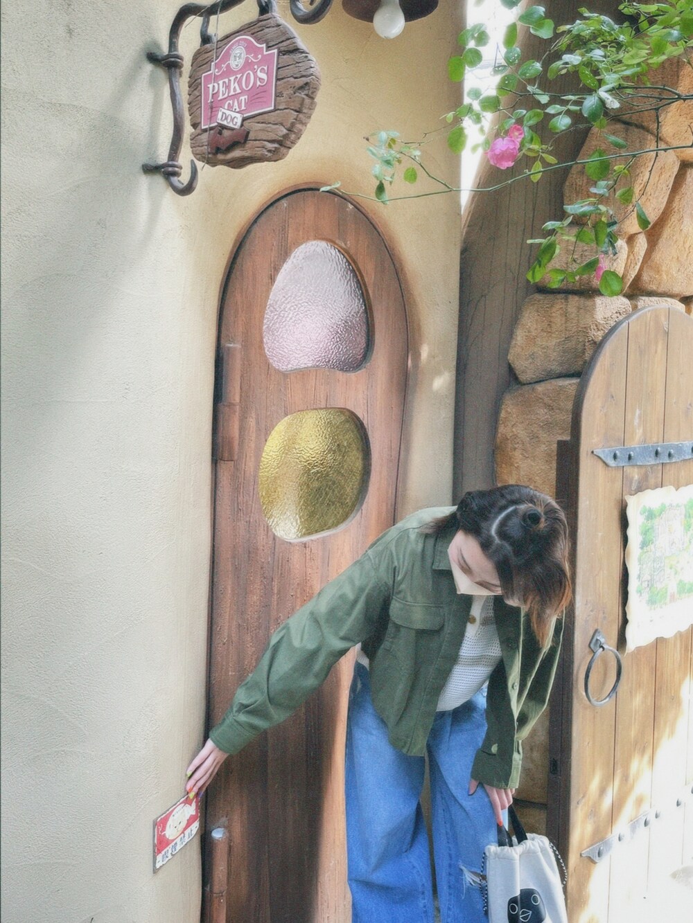 グリーン系のミリタリージャケット、ホワイト系のトップス、ブルー系のデニムパンツを着用したレディースの春コーディネートの2枚目の写真