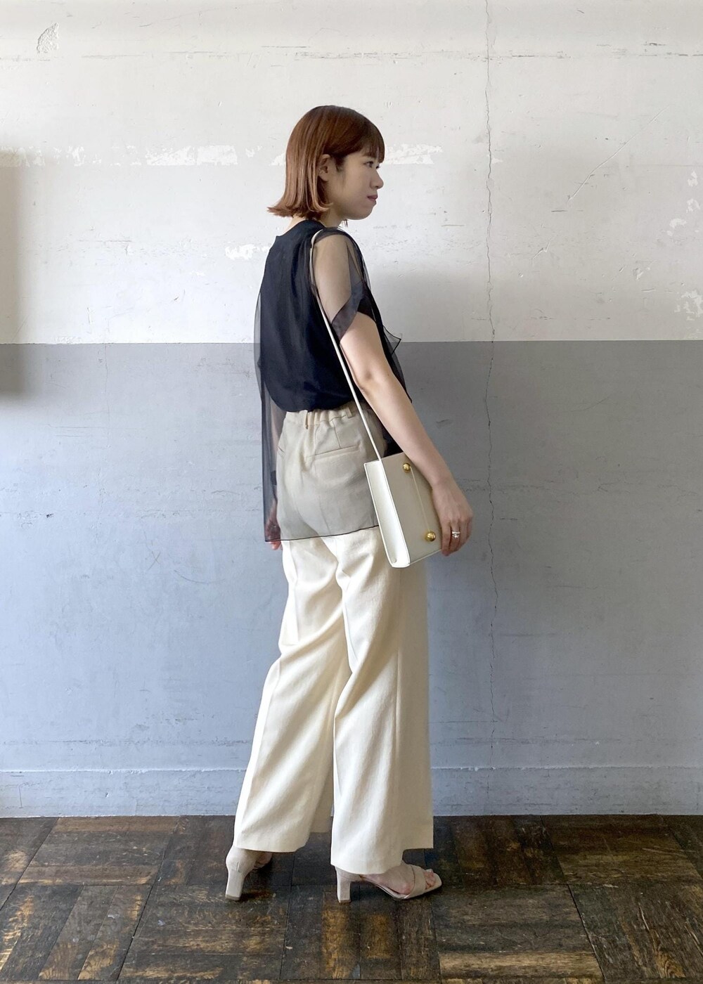 グレー系のショルダーバッグ、ベージュ系のサンダル、ベージュ系のスラックスを着用したレディースの夏コーディネートの2枚目の写真