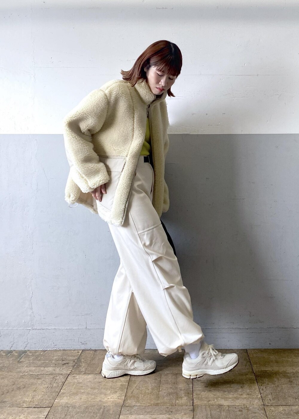 イエロー系のニット/セーター、ブラック系のハンドバッグ、ホワイト系のブルゾンを着用したレディースの秋コーディネートの4枚目の写真