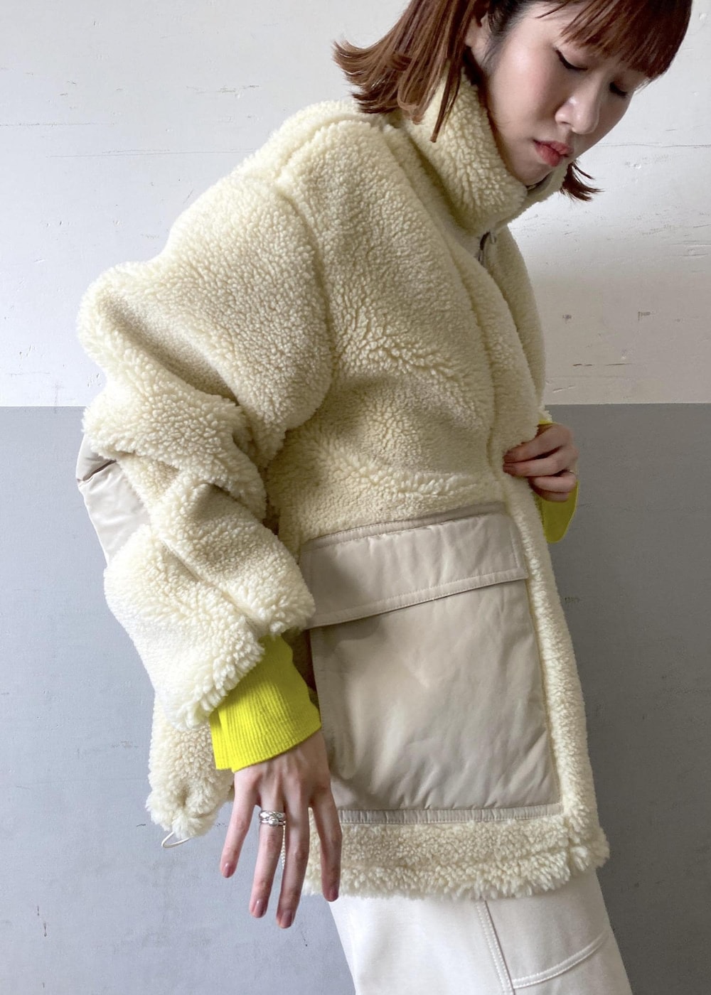 イエロー系のニット/セーター、ブラック系のハンドバッグ、ホワイト系のブルゾンを着用したレディースの秋コーディネートの7枚目の写真