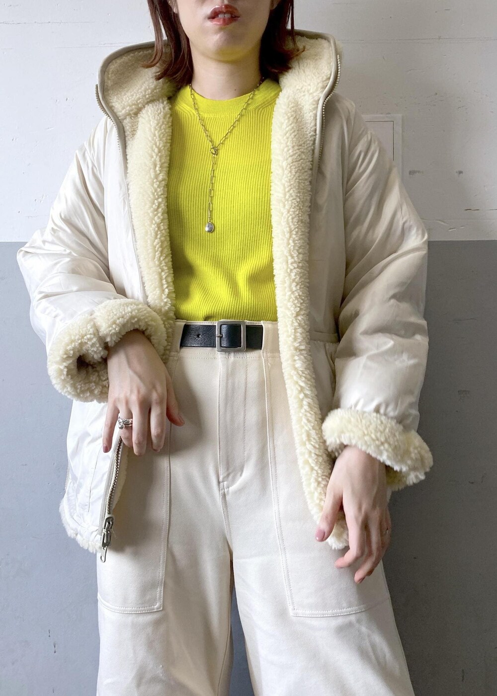 イエロー系のニット/セーター、ブラック系のハンドバッグ、ホワイト系のブルゾンを着用したレディースの秋コーディネートの10枚目の写真