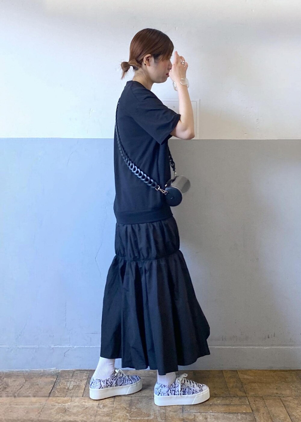 ブラック系のスニーカー、ブラック系のドラムバッグ、ブラック系のワンピースを着用したレディースの夏コーディネートの4枚目の写真