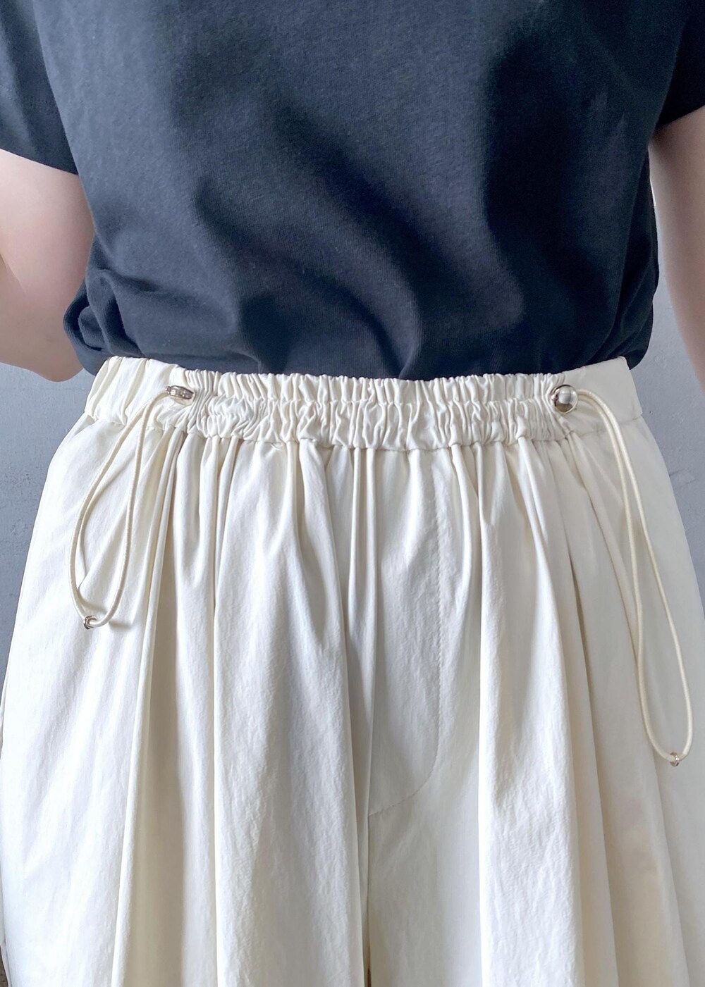 ベージュ系のトートバッグ、ブラック系のTシャツ/カットソー、ブラック系のサンダルを着用したレディースの夏コーディネートの10枚目の写真