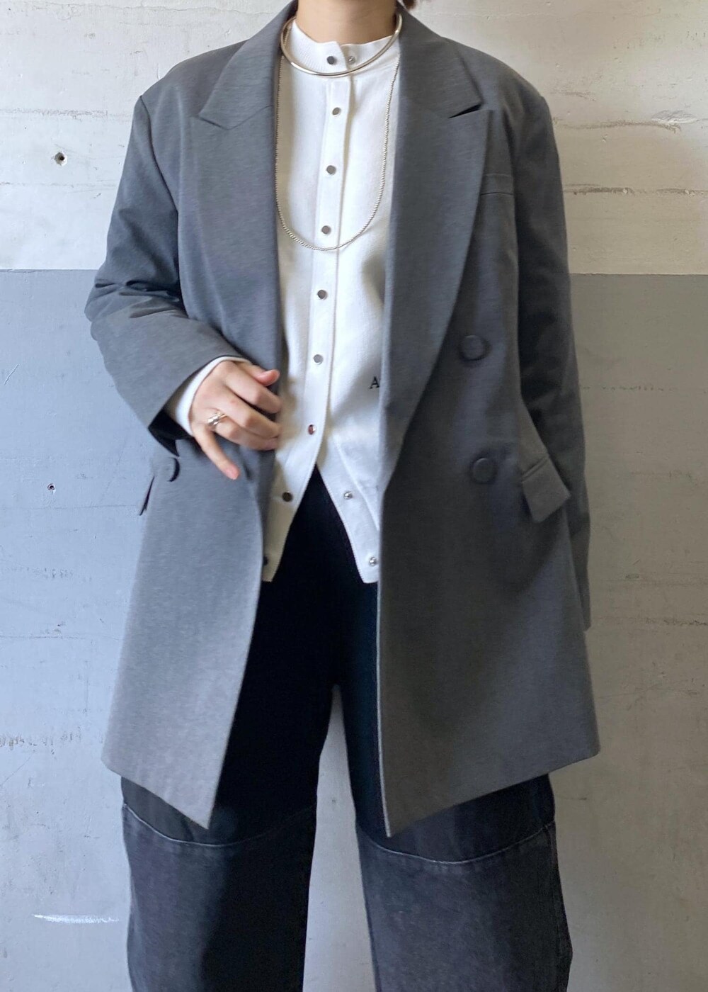 グレー系のテーラードジャケット、ブラック系のパンプス、ブラック系のショルダーバッグを着用したレディースの冬コーディネートの6枚目の写真