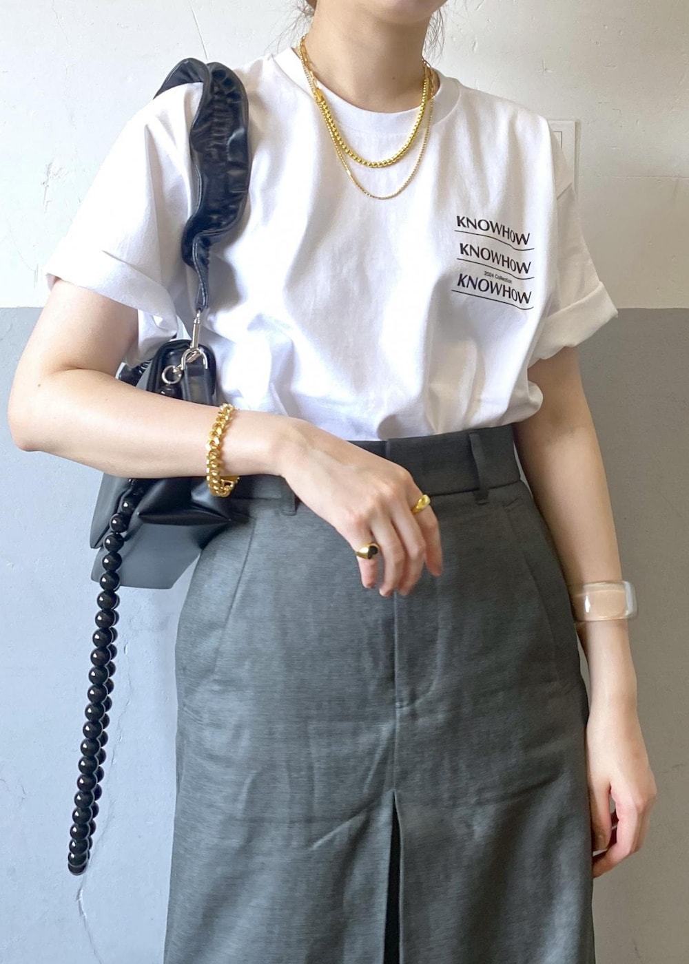 グレー系のスカート、ブラック系のショルダーバッグ、ホワイト系のTシャツ/カットソーを着用したレディースの夏コーディネートの5枚目の写真