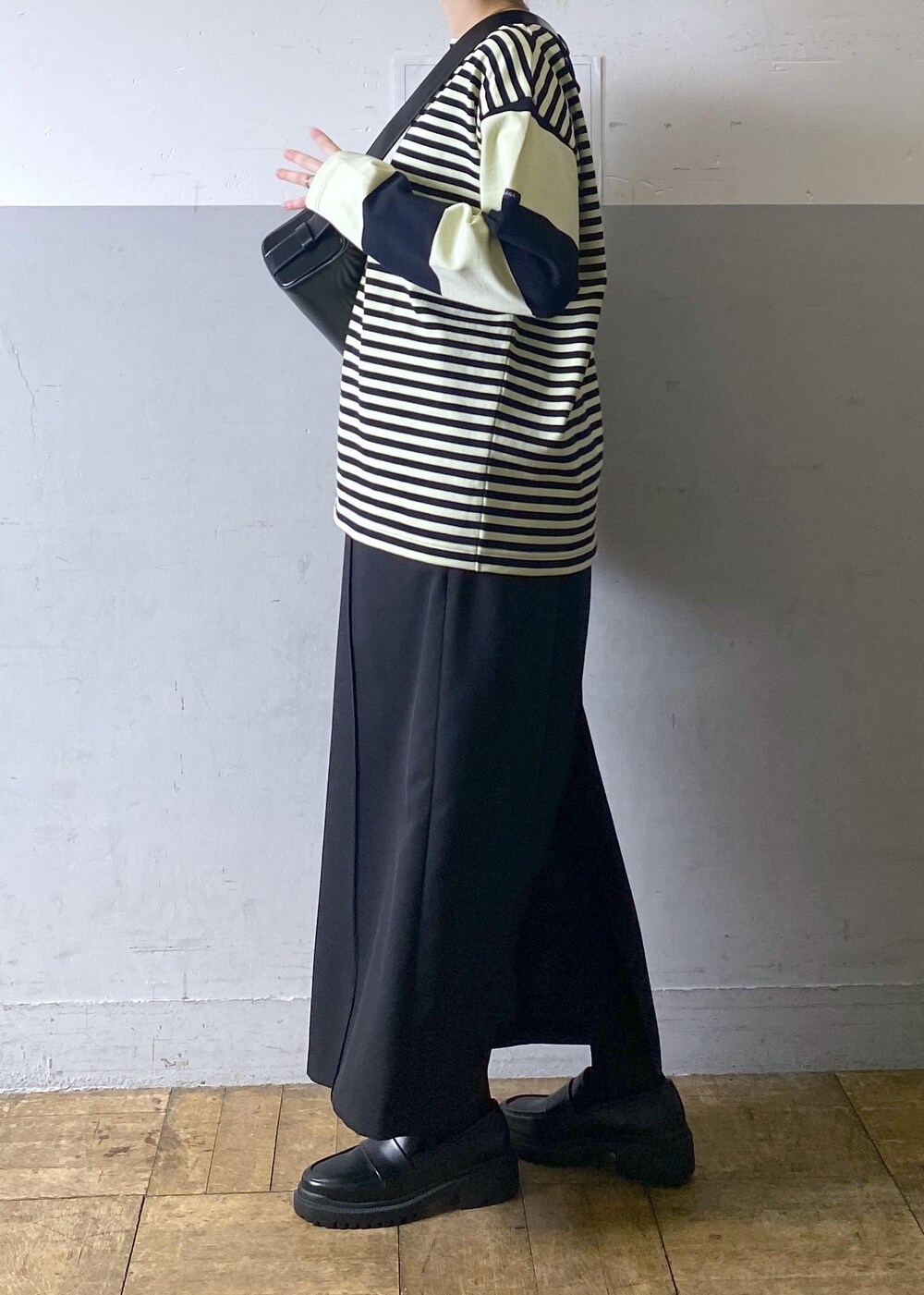 ブラック系のハンドバッグ、ブラック系のローファー、グリーン系のTシャツ/カットソーを着用したレディースの冬コーディネートの2枚目の写真