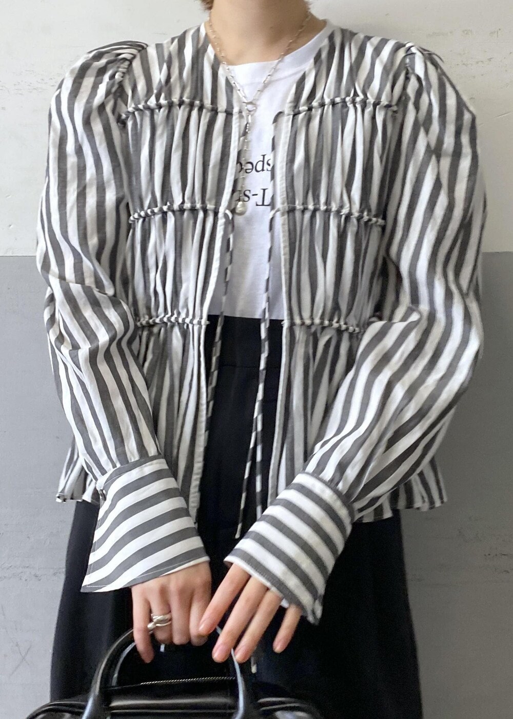 ホワイト系のシャツ/ブラウス、ブラック系のスラックス、ブラック系のボストンバッグを着用したレディースの春コーディネートの6枚目の写真