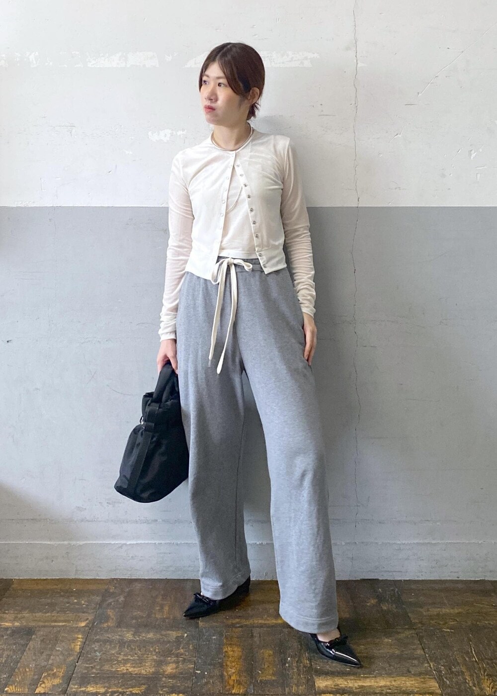 ブラック系のパンプス、ホワイト系のカーディガン/ボレロ、グレー系のスウェットパンツを着用したレディースの秋コーディネートの2枚目の写真