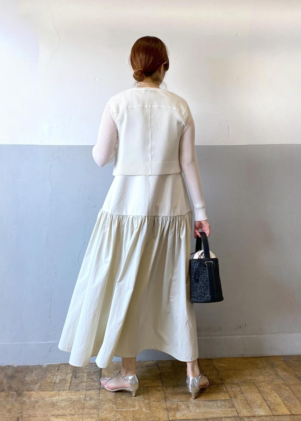 シルバー系のサンダル、ホワイト系のカーディガン/ボレロ、ブラック系のハンドバッグを着用したレディースの夏コーディネートの2枚目の写真