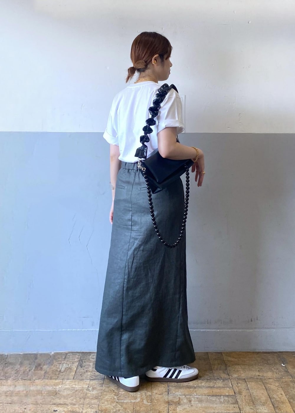 グレー系のスカート、ブラック系のショルダーバッグ、ホワイト系のTシャツ/カットソーを着用したレディースの夏コーディネートの3枚目の写真