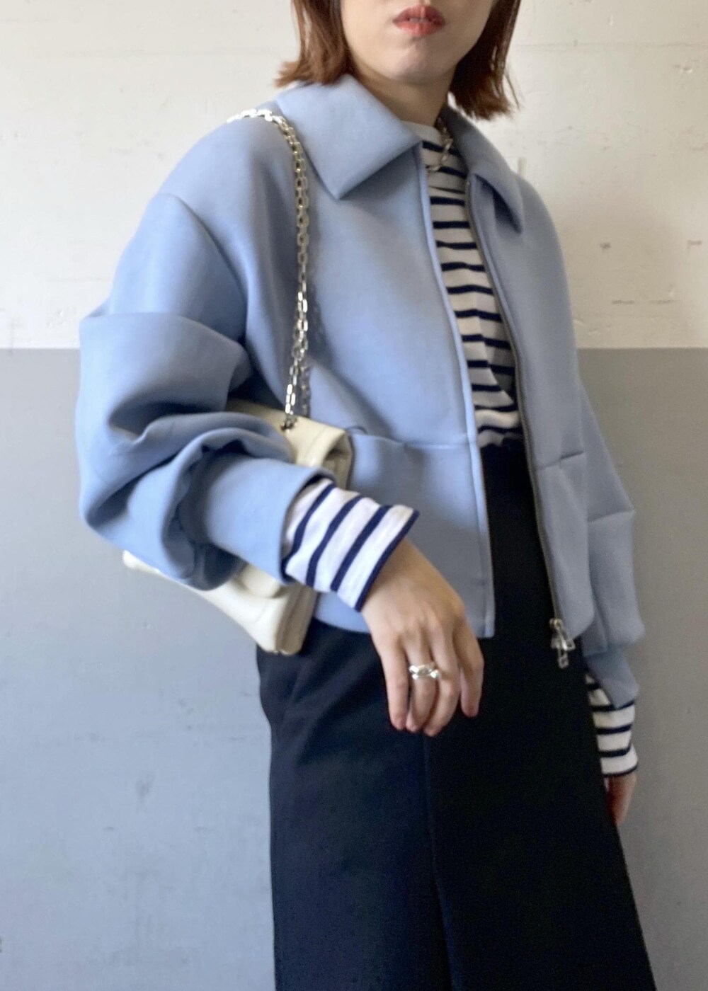 ブラック系のブーツ、ブラック系のスカート、ホワイト系のショルダーバッグを着用したレディースの秋コーディネートの7枚目の写真