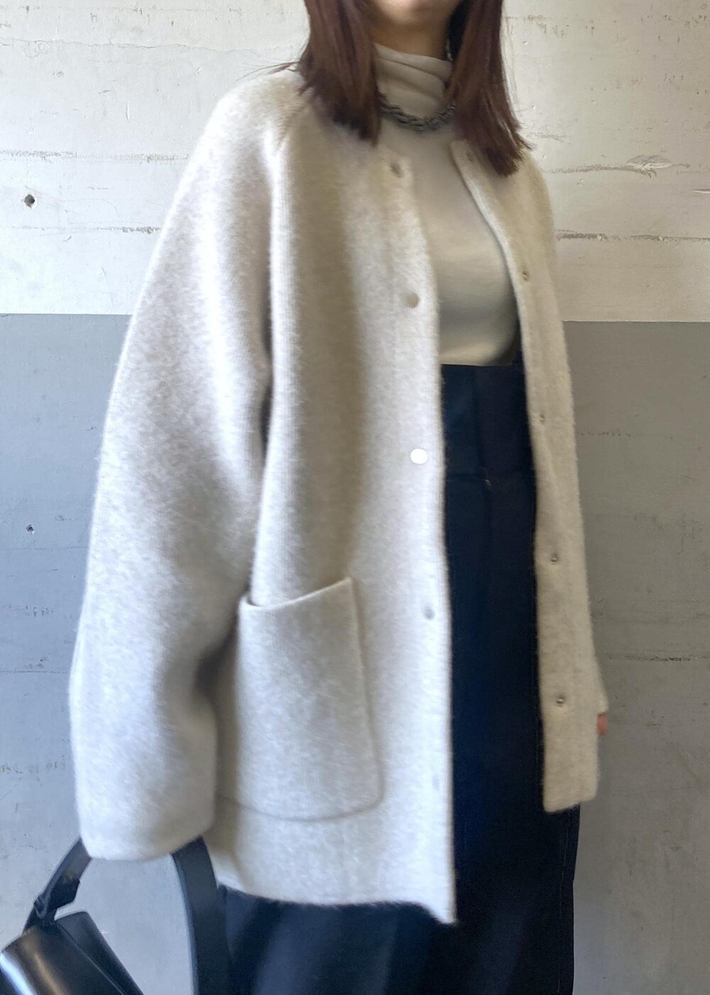 ホワイト系のカーディガン/ボレロ、ホワイト系のニット/セーター、ブラック系のハンドバッグを着用したレディースの冬コーディネートの6枚目の写真