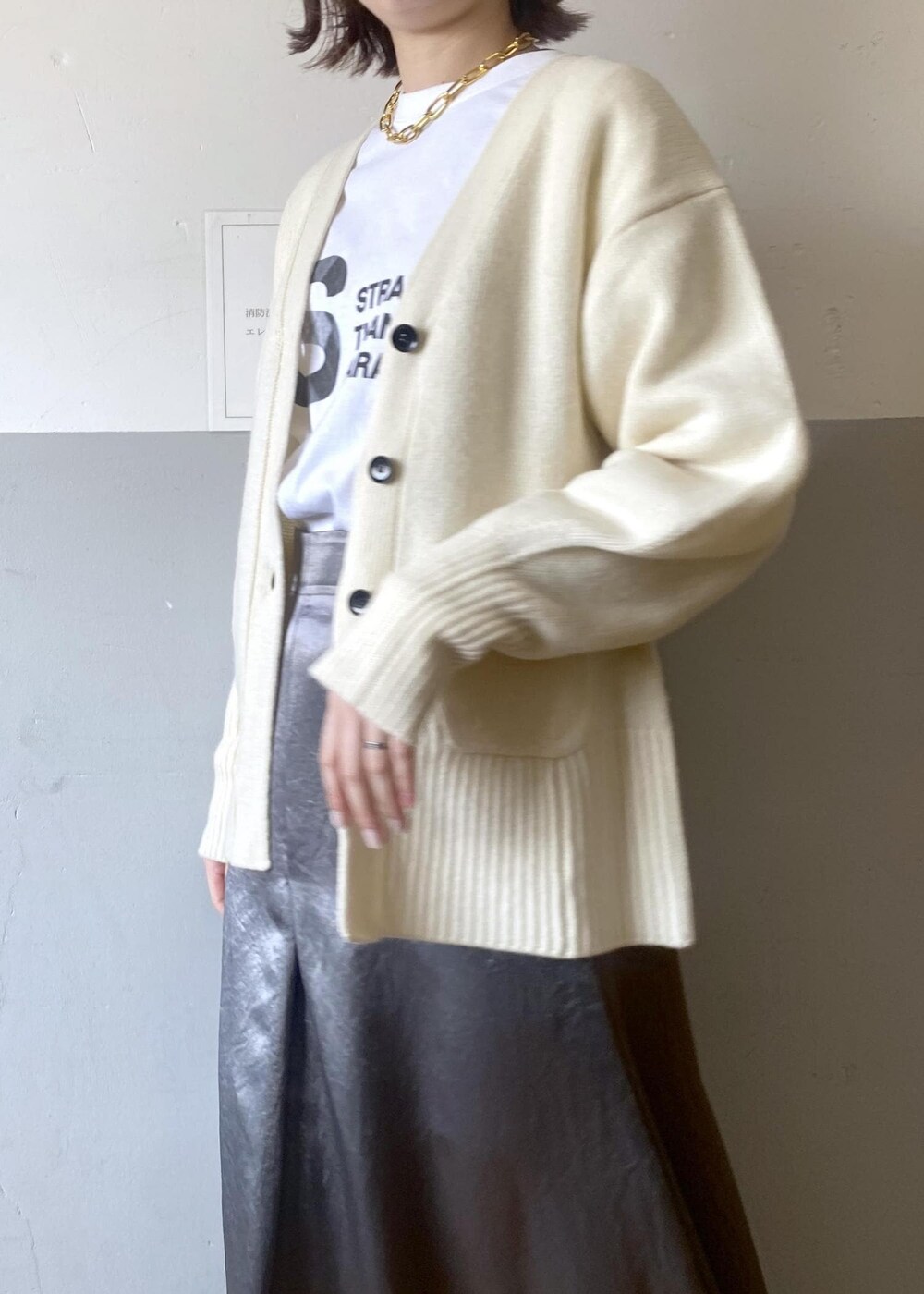 ホワイト系のTシャツ/カットソー、ブラック系のブーツ、ホワイト系のカーディガン/ボレロを着用したレディースの冬コーディネートの8枚目の写真