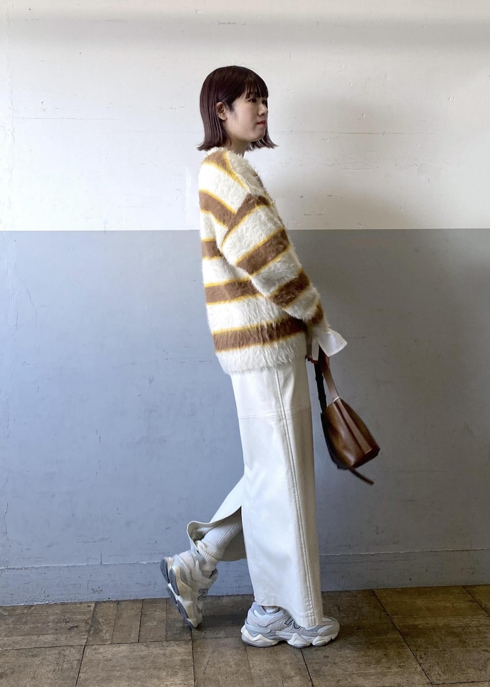 ホワイト系のスカート、ベージュ系のニット/セーター、ブラウン系のハンドバッグを着用したレディースの冬コーディネートの2枚目の写真
