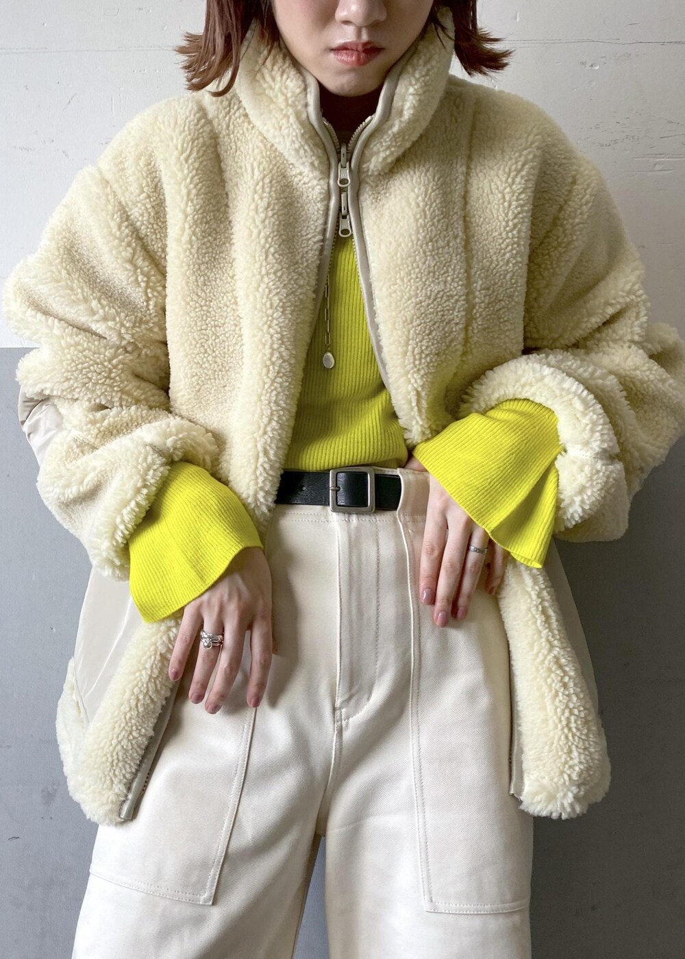 イエロー系のニット/セーター、ブラック系のハンドバッグ、ホワイト系のブルゾンを着用したレディースの秋コーディネートの6枚目の写真