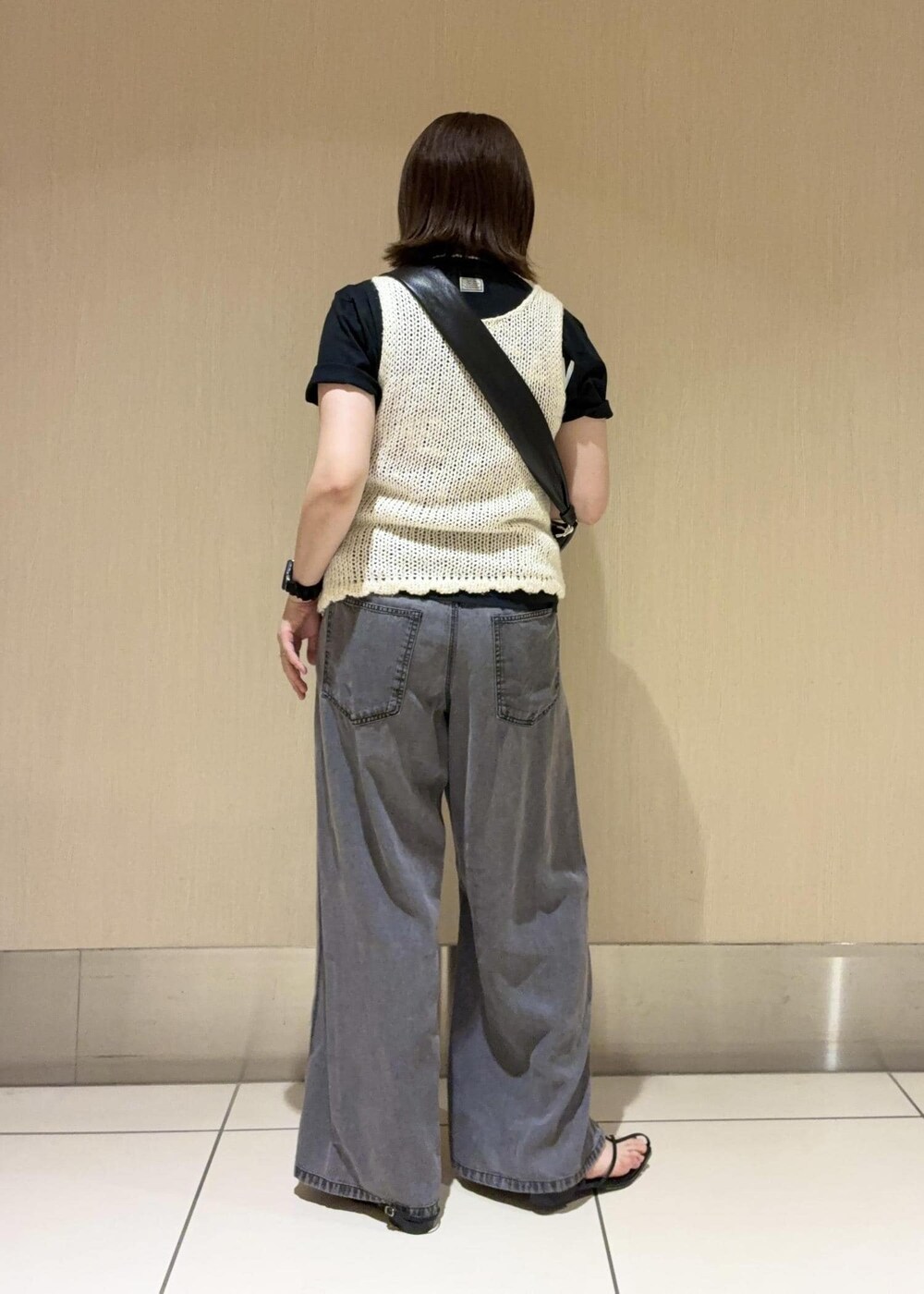 ブラック系のデニムパンツ、ブラック系のショルダーバッグ、ホワイト系のタンクトップを着用したレディースの春コーディネートの2枚目の写真