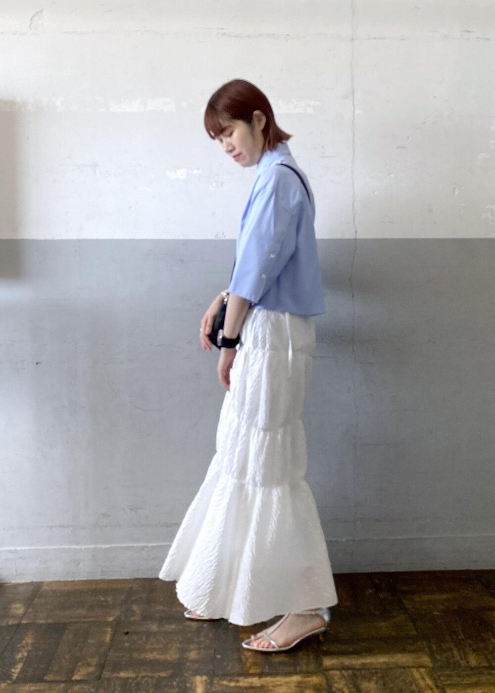 シルバー系のサンダル、ホワイト系のスカート、ブラック系のハンドバッグを着用したレディースの夏コーディネートの2枚目の写真