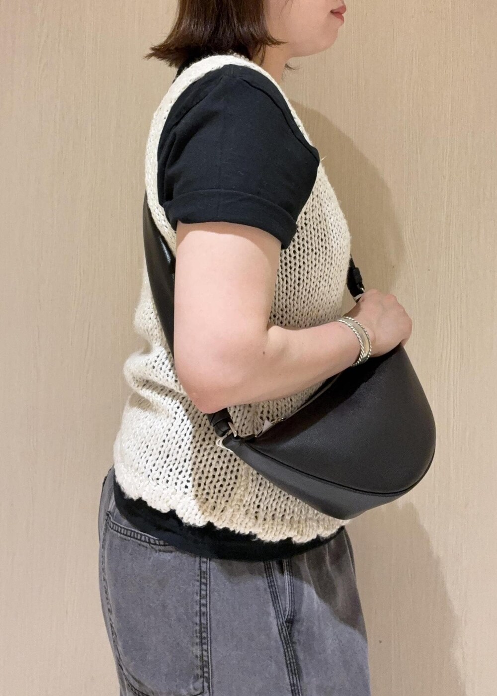 ブラック系のデニムパンツ、ブラック系のショルダーバッグ、ホワイト系のタンクトップを着用したレディースの春コーディネートの6枚目の写真