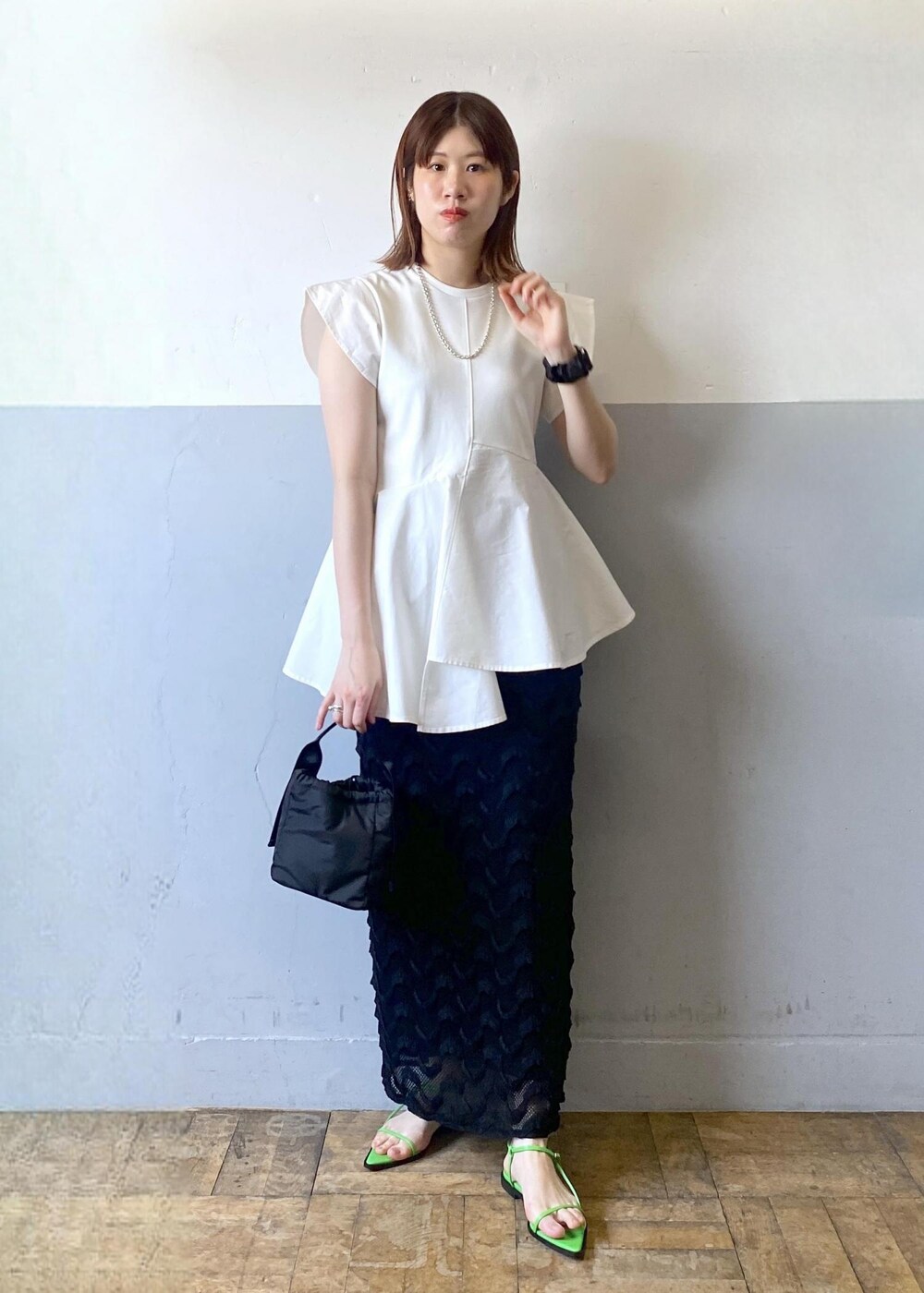 ブラック系のハンドバッグ、グリーン系のサンダル、ブラック系のスカートを着用したレディースの春コーディネートの2枚目の写真