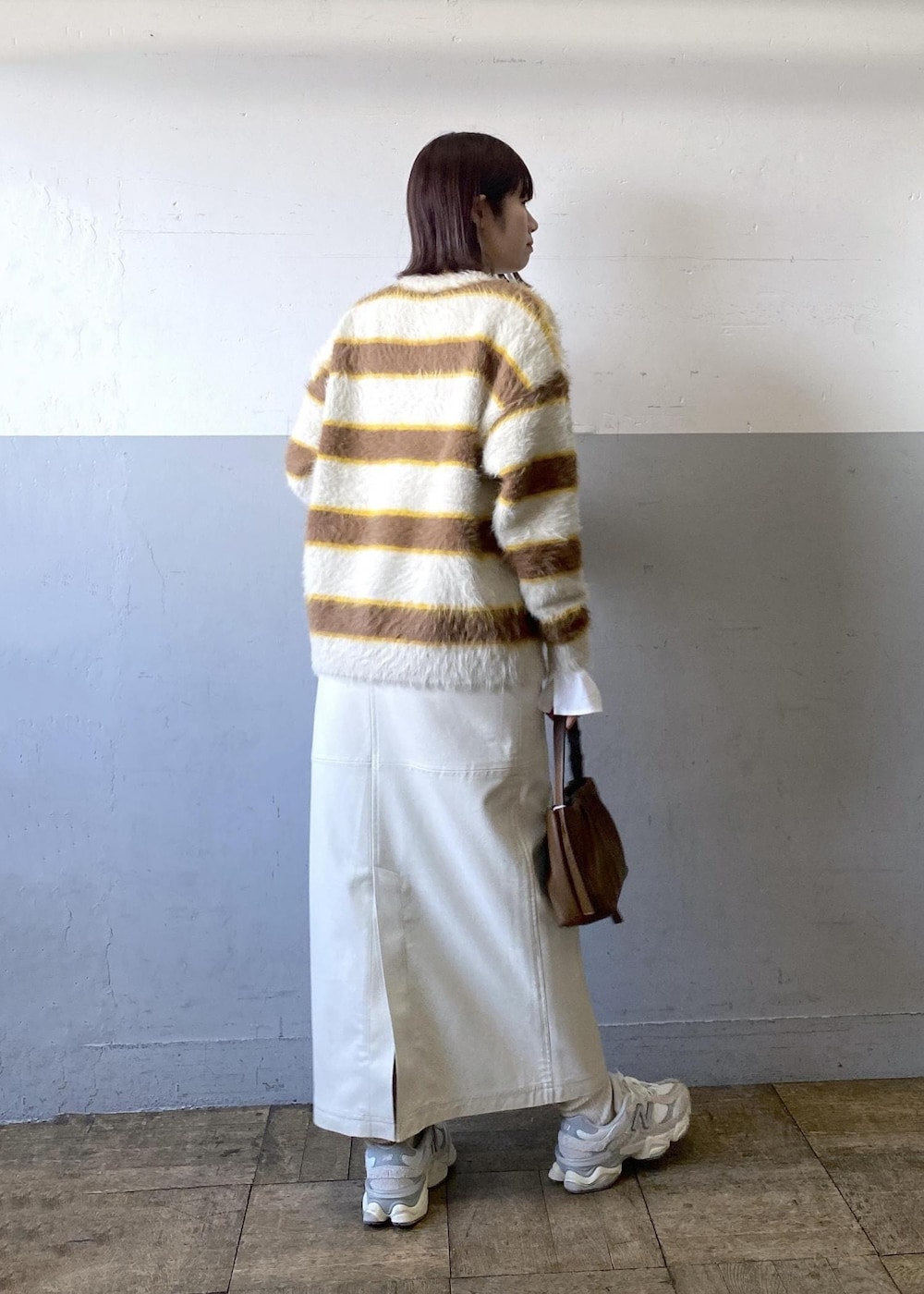 ホワイト系のスカート、ベージュ系のニット/セーター、ブラウン系のハンドバッグを着用したレディースの冬コーディネートの3枚目の写真