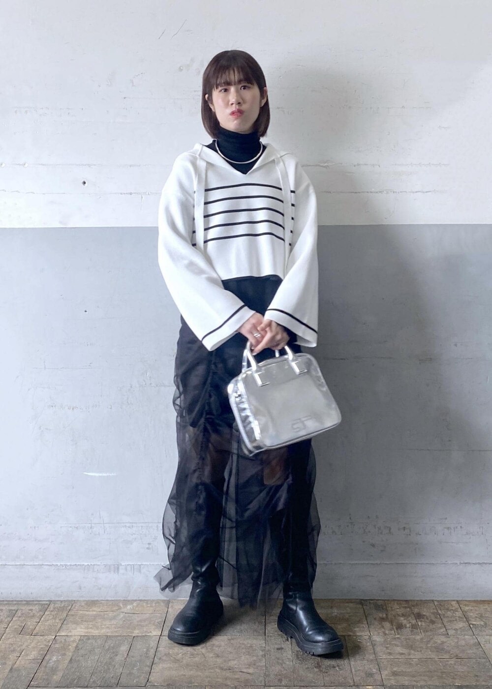 シルバー系のボストンバッグ、ブラック系のニット/セーターを着用したレディースの冬コーディネートの2枚目の写真